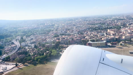 Cityscape-seen-from-airplane-window-during-ascent,-engine-in-foreground