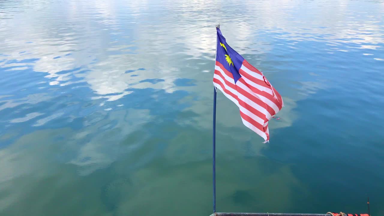 la bandera de malasia volando sobre el hermoso agua.