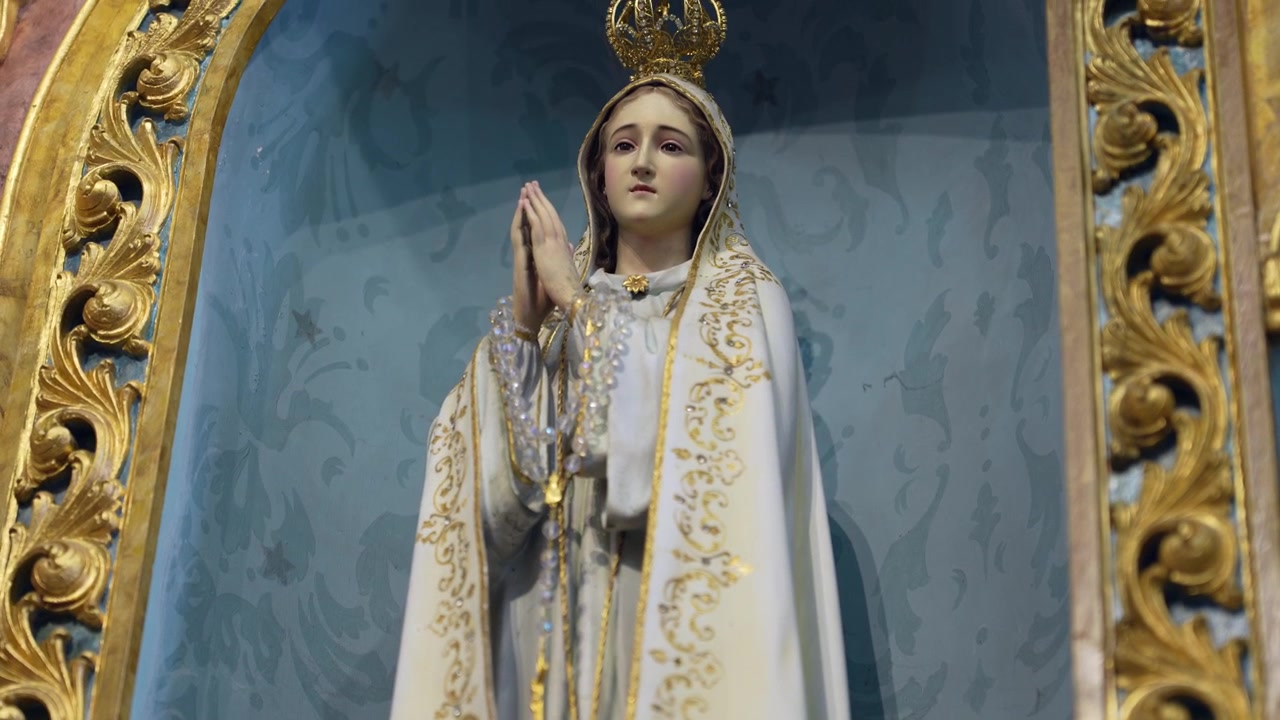 Figura religiosa con un elaborato paramento sacro, caratterizzato da motivi ricamati in oro, appeso in un ambiente ecclesiastico