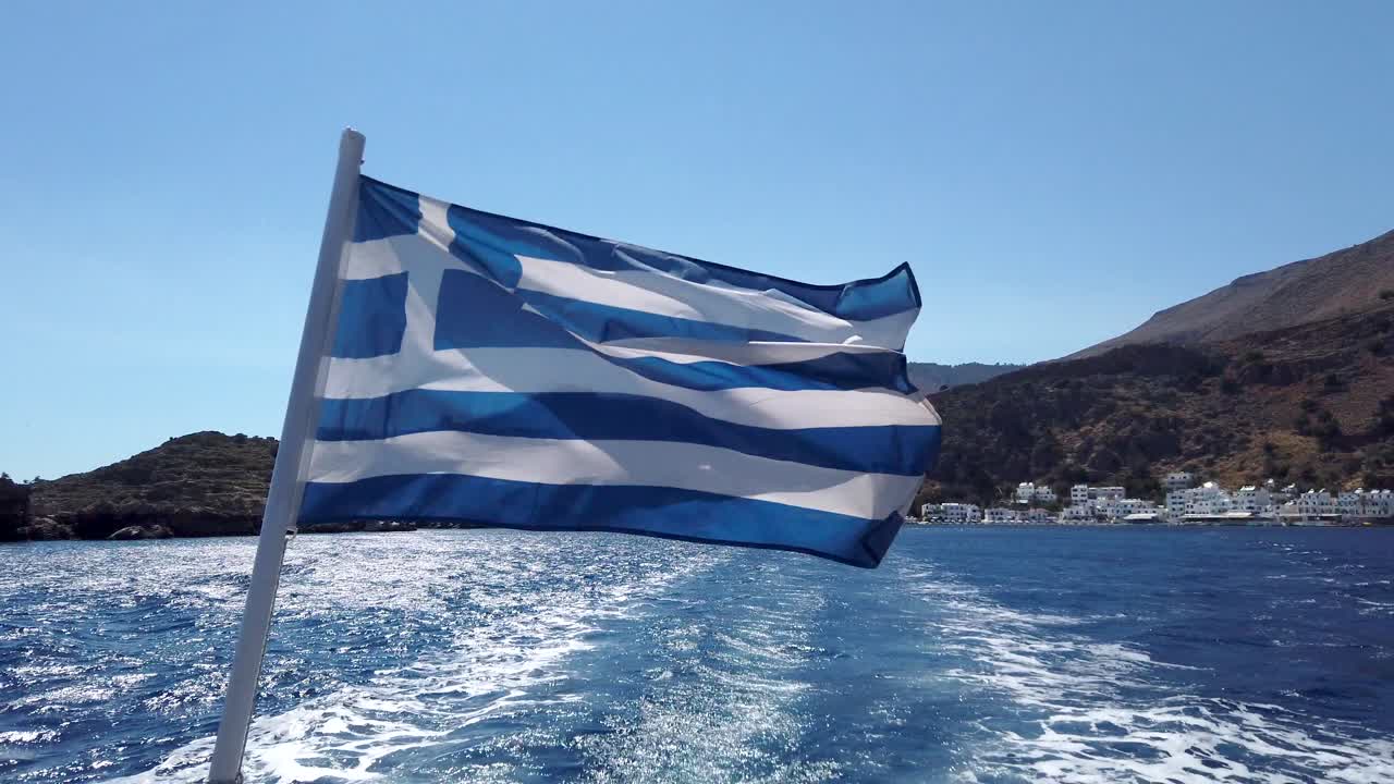 bandera griega en un barco que sale de loutro