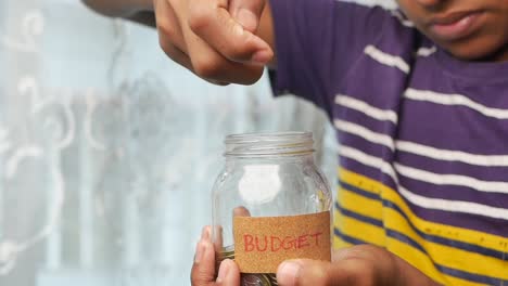 Slow-motion-of-boy-saving-coins-in-a-jar-white-sited