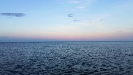 Low-fast-flying-drone-shot-over-calm-ocean-during-evening-sunset