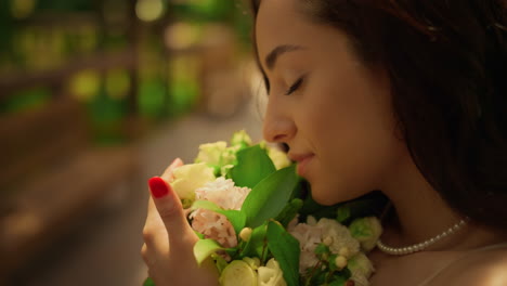 brunette bride posing with flowers in garden. woman smelling flowers outdoors