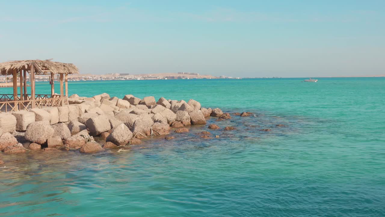 Seaside rocks and a thatched hut with turquoise waters in Hurghada, Egypt, calm vibe