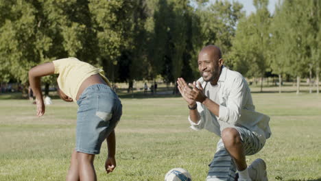 Black-boy-doing-cartwheel-in-park-while-father-applauding-him.