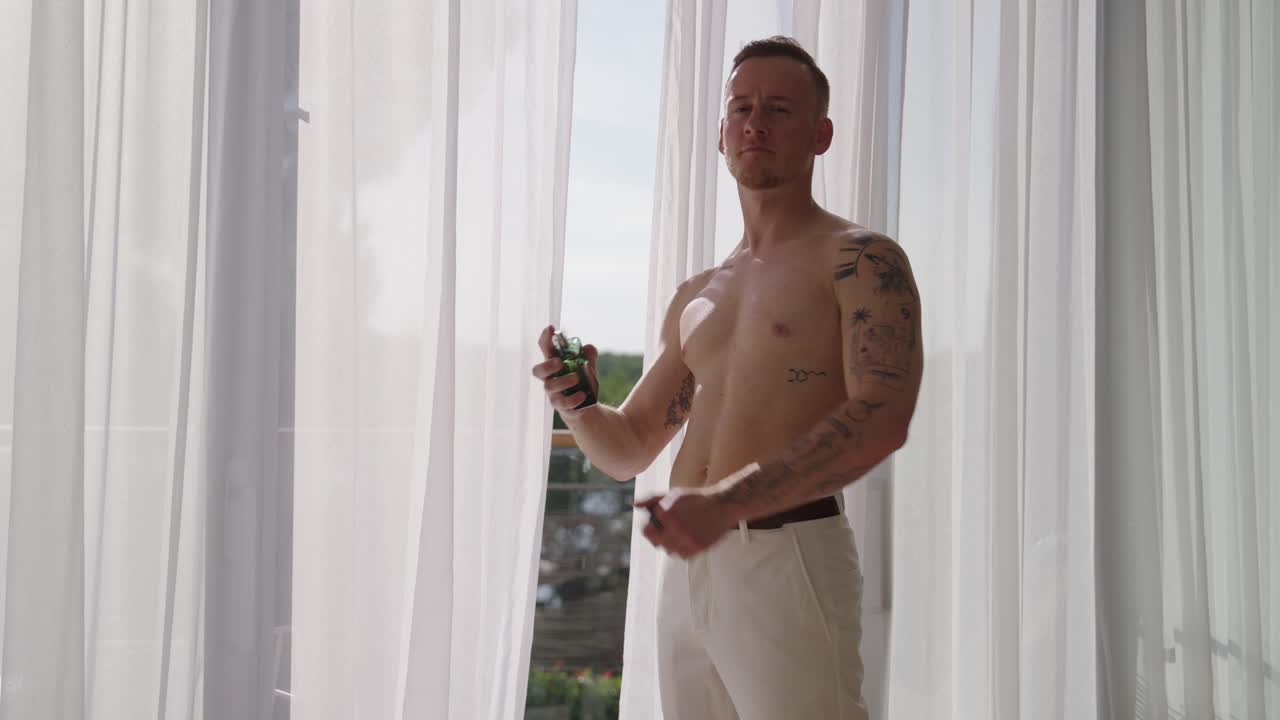 Groom uses perfume before wedding, side view