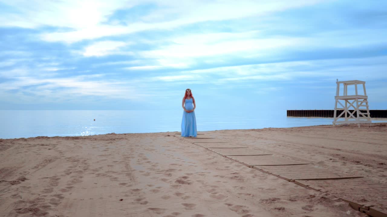 해변에서 긴 드레스를 입은 임산부. 임신 개념