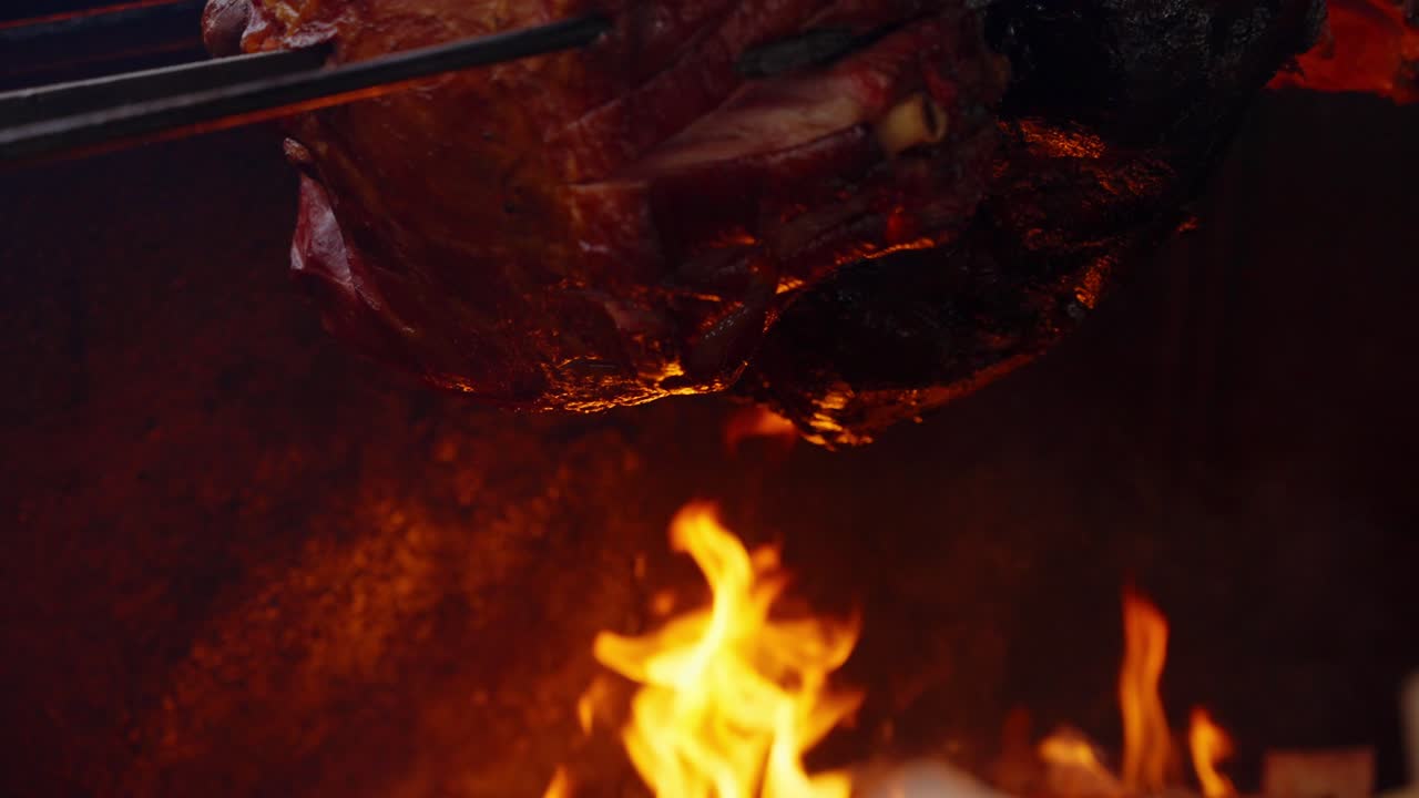 Carne de porco sobre chamas saltitantes com brilho forte e superfície assada rica captando reflexos quentes