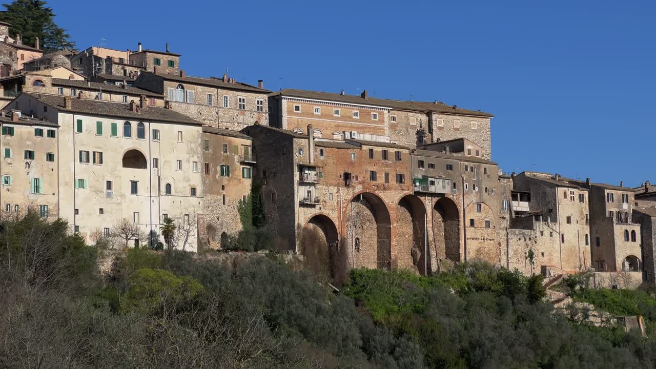 Panning close-up shot of the architectural details, including ancient arches and windows, of the historic buildings built on the cyclopean walls of Amelia, Umbria, Italy