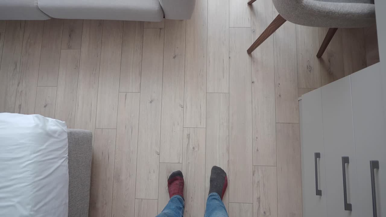 View of feet with mismatched socks on wooden floor