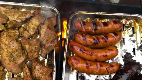 slices of marinated meat and sausages grilled on metal trays outside the house during the daytime