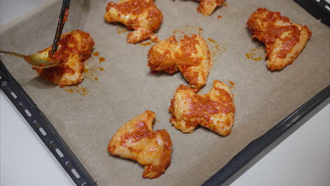 cubrir las alas de pollo con salsa caliente colocadas en una sábana de hornear