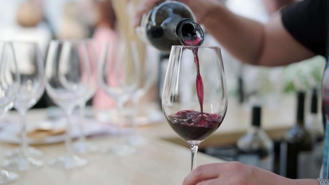 클로즈업: 익명의 웨이터 손이 술잔에 포도주를 고, 젊은 여성 손이 레스토랑 내부에서 음료와 함께 포도주 술잔을 고 있다.