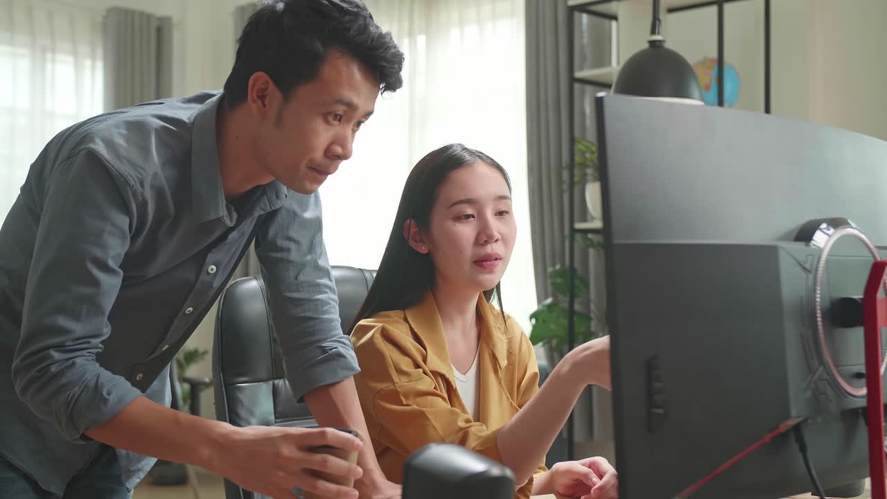 Asian Female Has Discussion With Male While Work On Computer In The Office