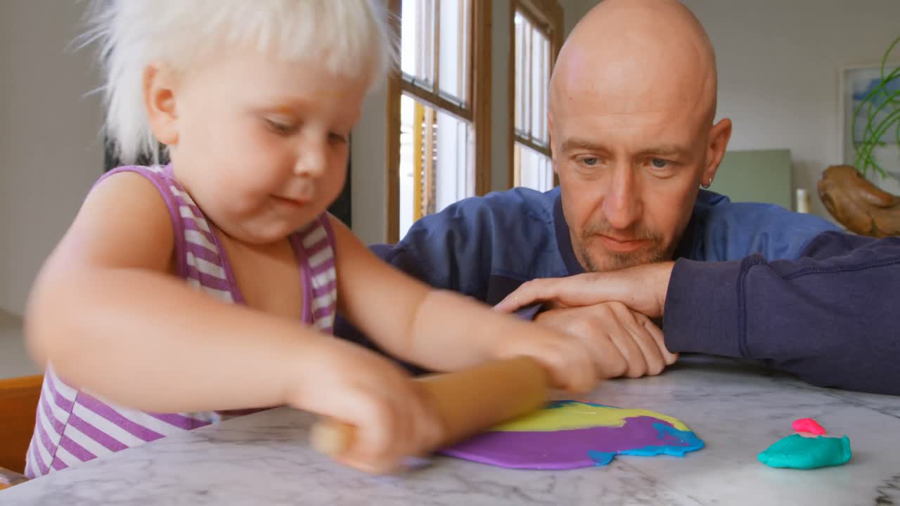 Vader en dochter spelen samen met klei in een gezellig huis 4k