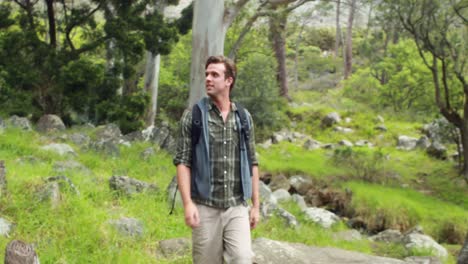 smiling man hiking through a forest