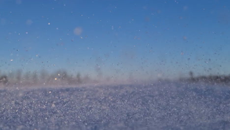 Niedrigwinkelaufnahme-Von-Winterschnee-Eiskristallen-Im-Wind-Am-Sonnigen-Tag-Des-Blauen-Himmels