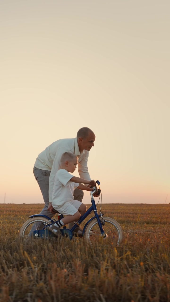 Father Teaching Young Son to Ride a Bicycle in a Field