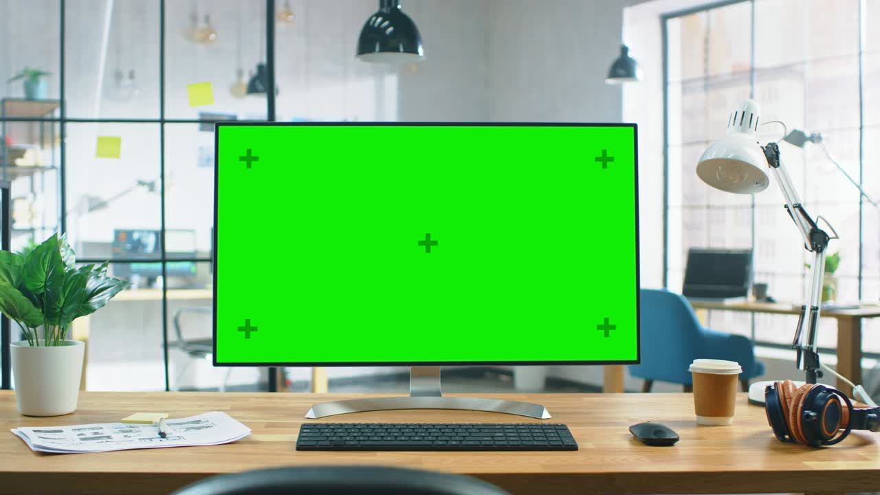 현대적인 크리에이티브 오피스의 책상 위에 서있는 넓은 녹색 모형 화면 데스크 컴퓨터.