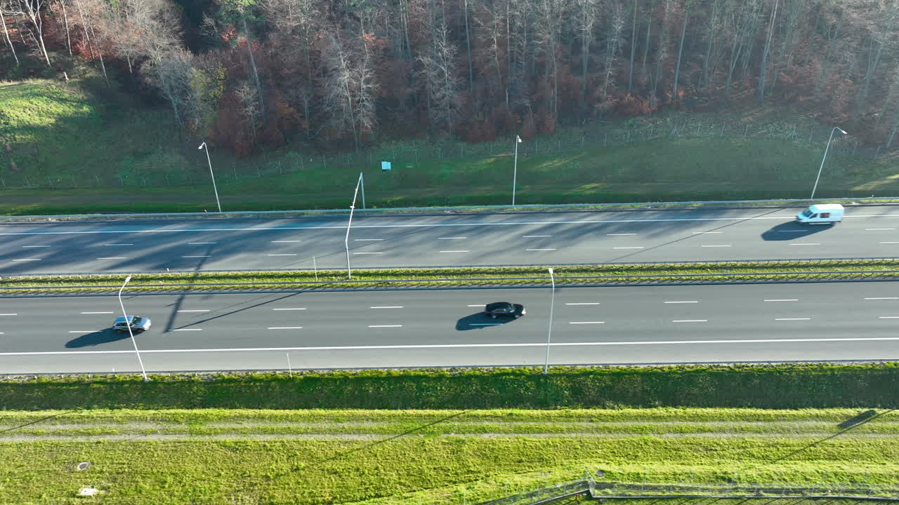 Aerial view of multi-lane highway with moving cars in bright daylight and long shadows