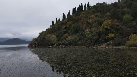 Nahaufnahme-Des-Wassers-Des-Pivsko-sees-Mit-Dichtem-Unterholz-Und-Umgeben-Von-Einer-Bergkette-Auf-Allen-Seiten-In-Montenegro