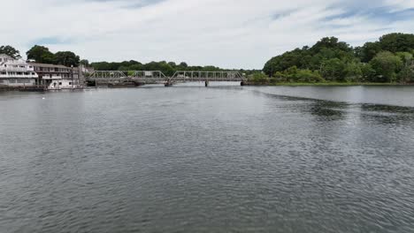 A-low-angle-aerial-view-over-the-Saugatuck-River-in-Connecticut-on-a-beautiful-day-with-blue-skies-and-white-clouds