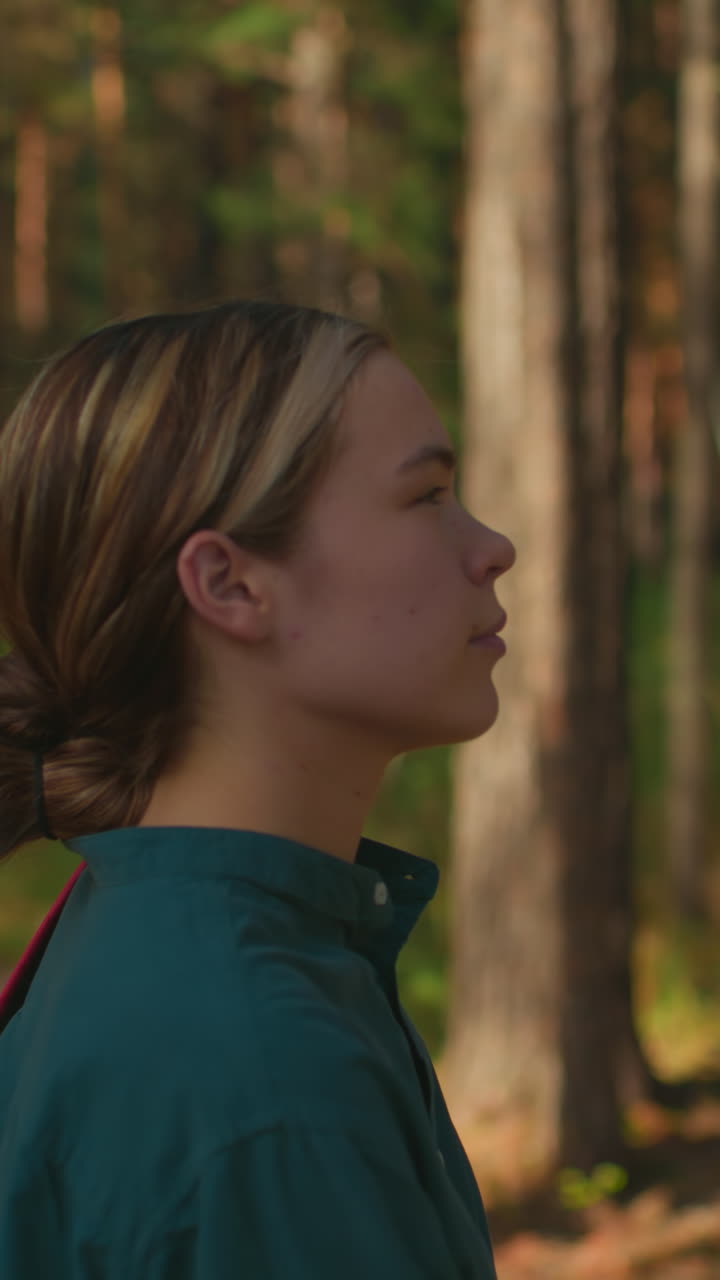 dos mujeres caminando por un bosque iluminado por el sol, una con una mochila roja y una tela cubierta, otra con un pañuelo azul y una mochila, la luz del sol se filtra a través de los árboles, reflejándose suavemente en sus rostros