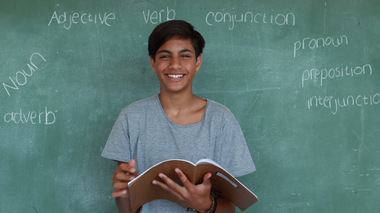 retrato de un escolar escribiendo en un cuaderno contra una pizarra verde
