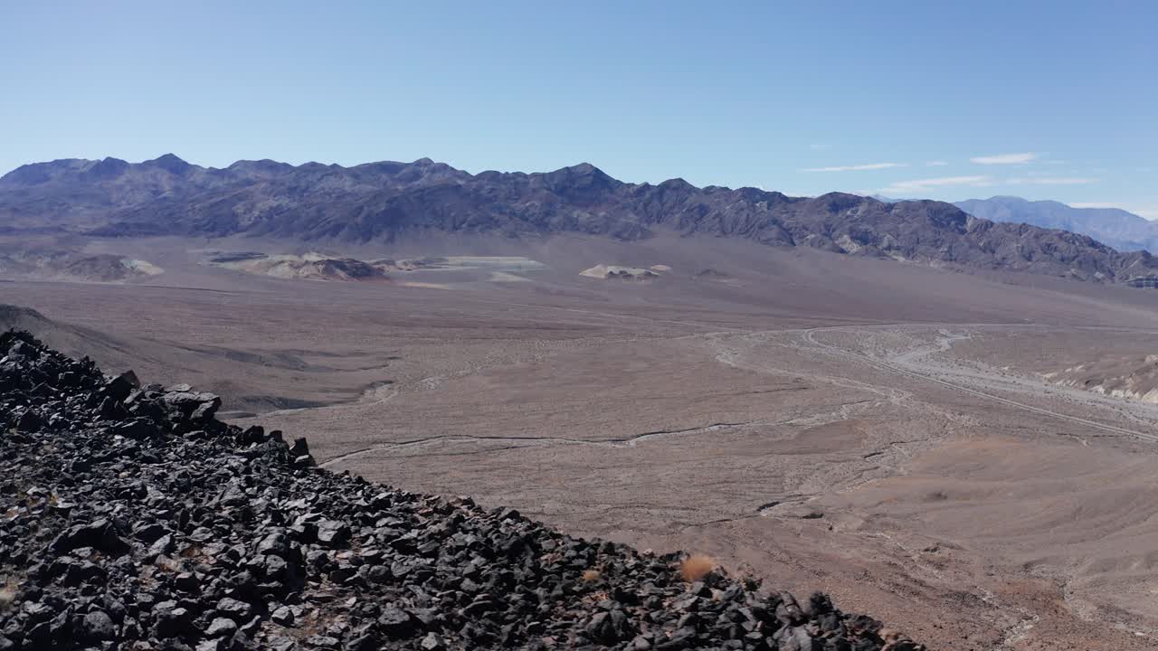 Close-up aerial panning shot of a rocky desert ridge above the otherworldly landscape in Death Valley, California. 4K