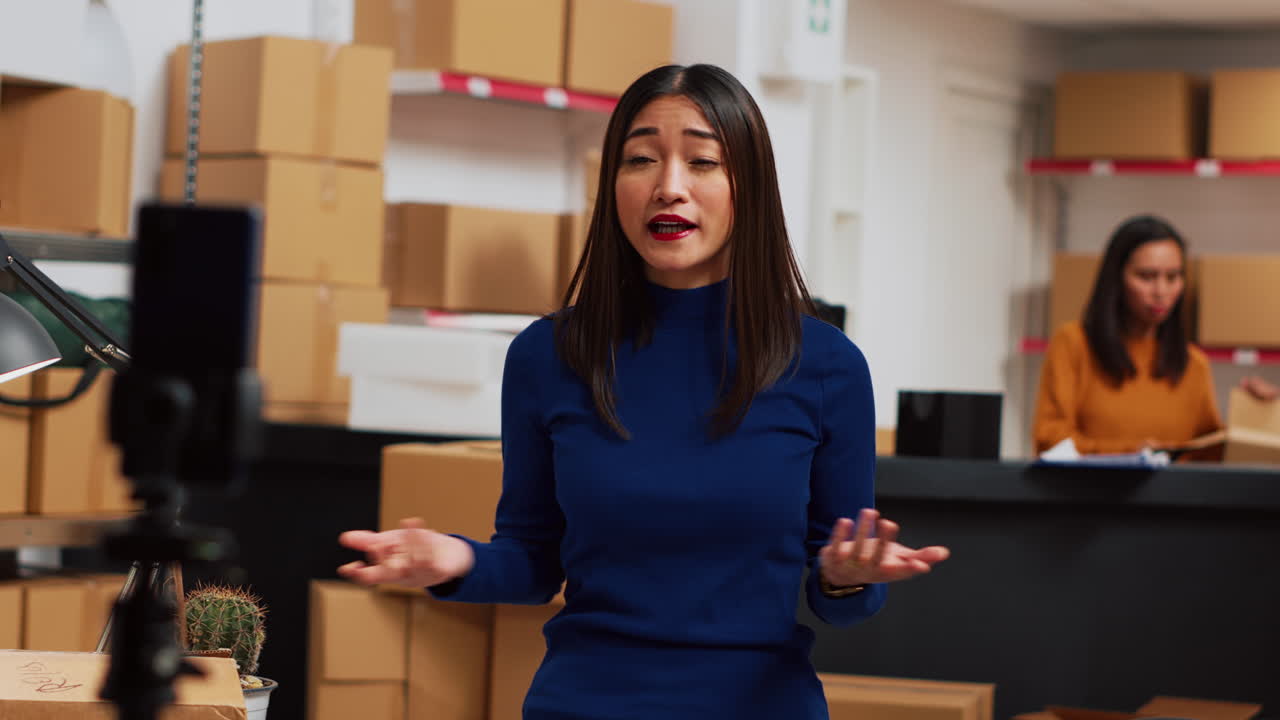 Woman filming in a warehouse surrounded by boxes