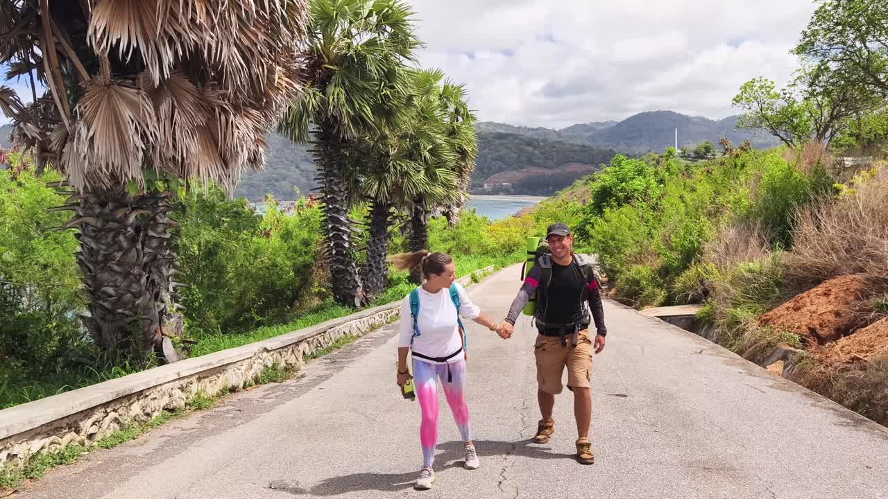 Casal em Caminhada numa Estrada com Vista para o Oceano