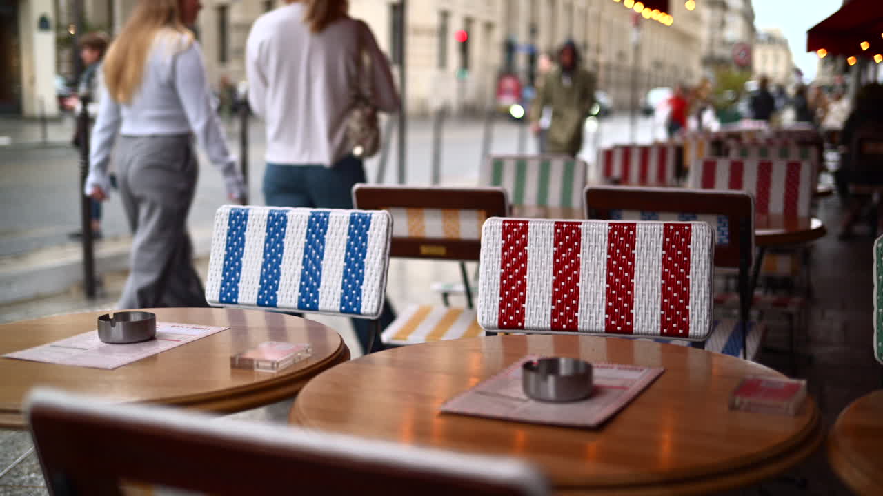 Tables at a cafe with blurred people walking in the rain on the background