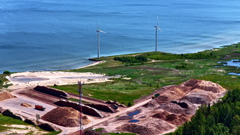 aerial view of coastline with wind turbines and wood processing facility at baltic sea