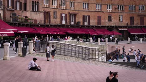 stabilized shot of plaza with old buildings and people in tuscany, italy, on a cloudy day.