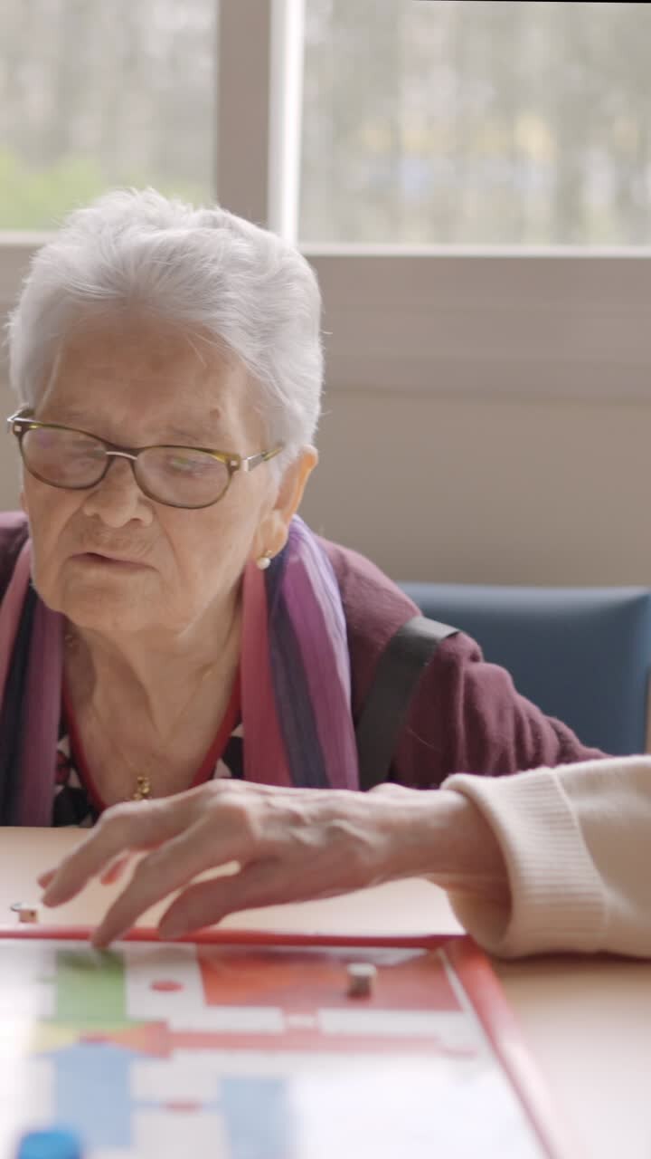 Three old friends playing board game in a nursing home
