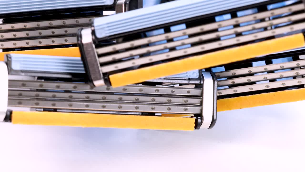 흰색 배경에서 회전하는 일부 일회용 면도기 면도날의 클로즈업 보기, 4k의 매크로 샷