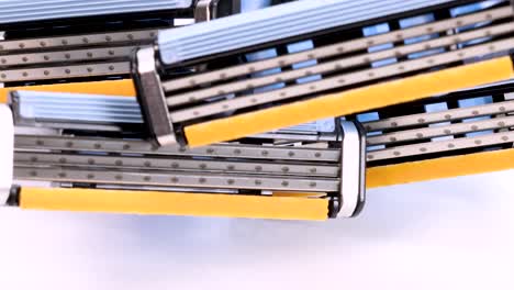 Close-up-view-of-some-disposable-shaver-razor-blades-rotating-on-white-background,-macro-shot-in-4k