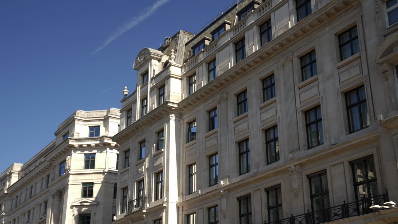 Slow gimbal orbit around iconic London style historical buildings in the capital city of england on bright sunny day with blue sky and punchy shadows