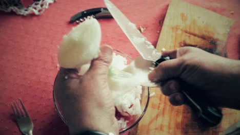 first person from the top view of hands cutting a onion in small pieces to make salad