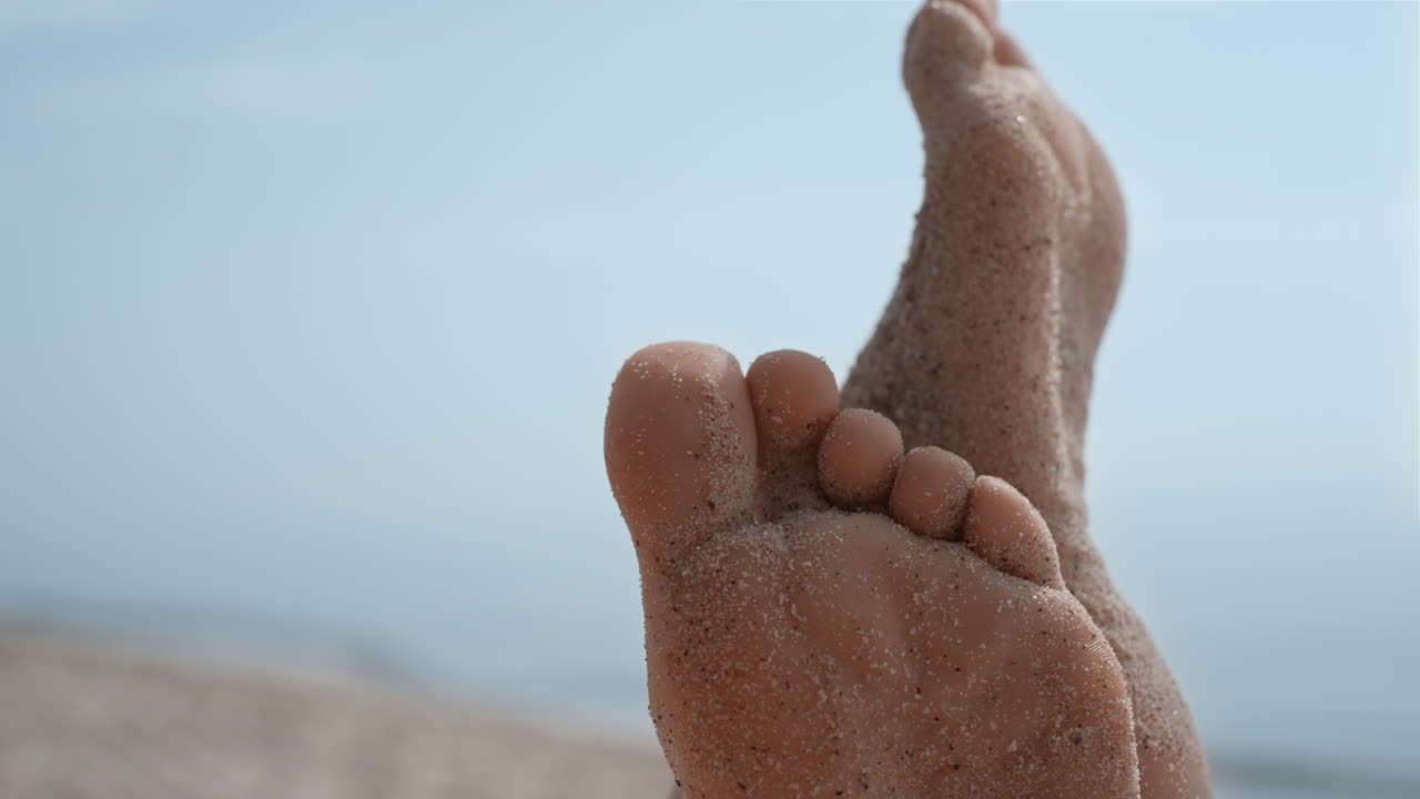 해변 모래로 인 맨발의 여자. 맨발의 소녀가 다리를 들어 올리고 있다.