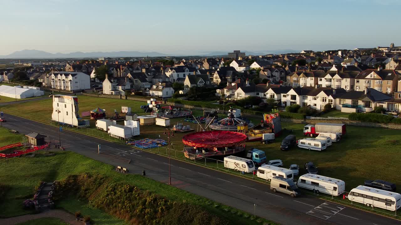Vibrant fairground rides aerial view circling above Holyhead Welsh coastal town waterfront