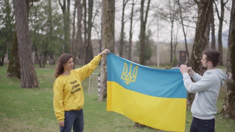 the girl and the boy are holding and walking with the ukrainian flag. symbol of empathy. the inscription on the girl's sweater: "your opinion is important"