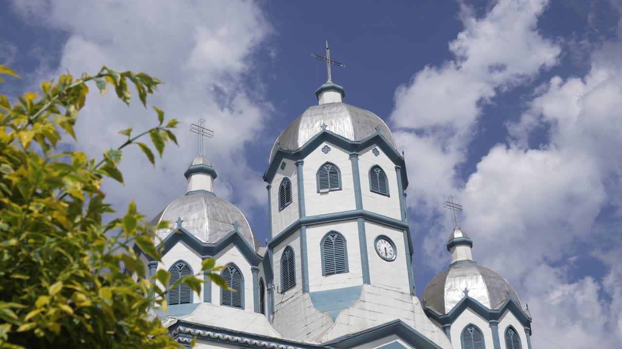 Leaves frame silver-domed church towers in Filandia as the camera reveals, Close up