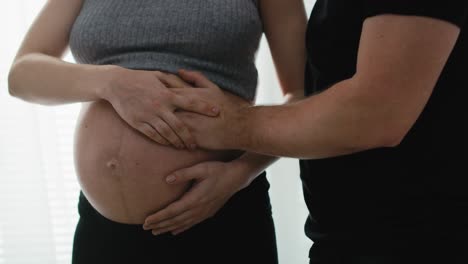 detalle de la madre en el embarazo avanzado y el futuro padre sintiendo los movimientos del bebé.