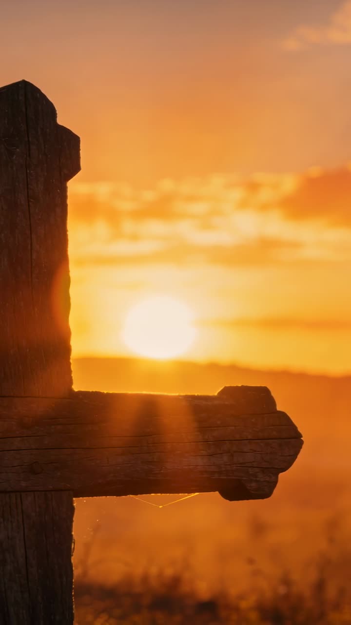 Video verticale: Croce di legno in piedi a sinistra mentre il sole sorge, illuminando l'erba, una ragnatela, con un bagliore (flare) e spazio per il testo.