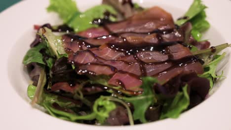 a dish of sliced smoked tuna and salad, topped with sweetened vinegar ready to be eaten