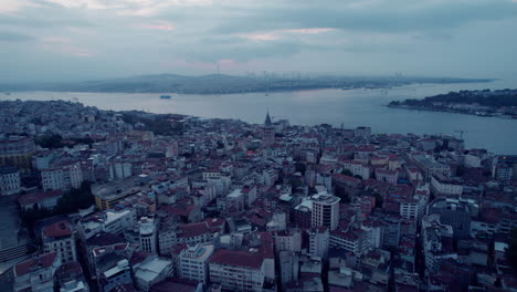 Aerial-cityscape-on-a-grey-and-cloudy-day-with-river-and-the-Galata-tower,-Istanbul,-copy-space-and-slowmo