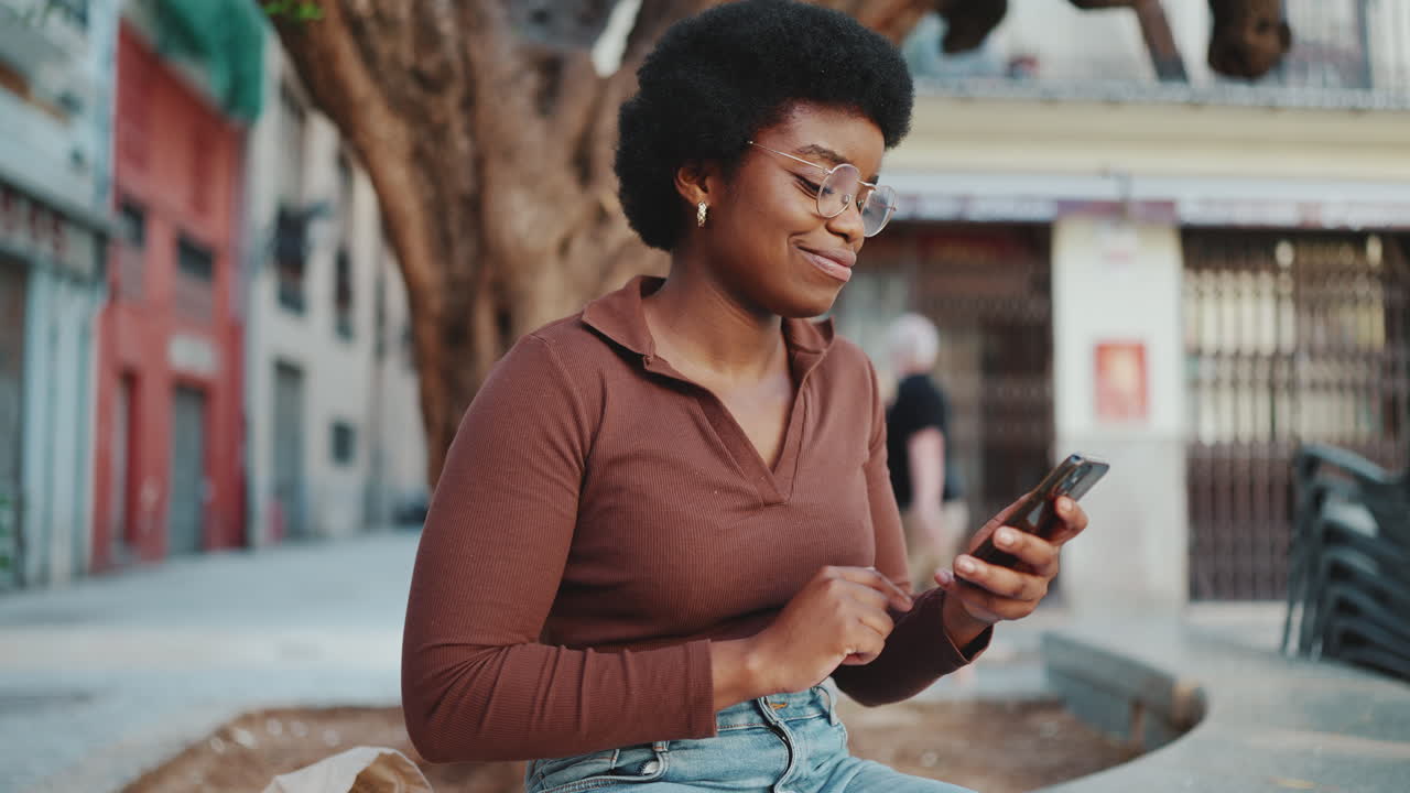 Pretty dark-skinned girl checking her smartphone on the street