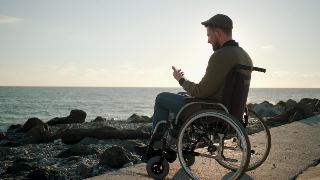 hombre discapacitado usando el teléfono en la playa