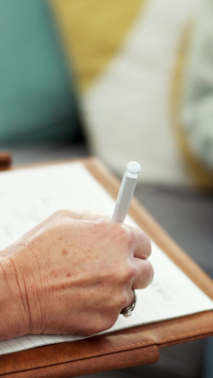Primo piano di una persona che scrive su un blocco per appunti